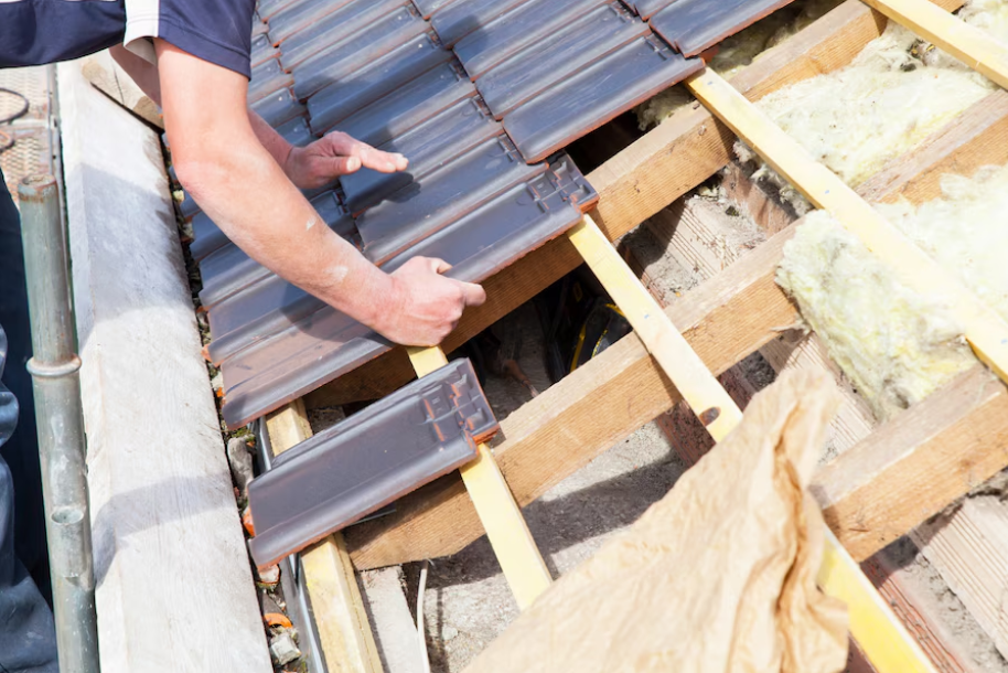 man putting shingles on a new roof